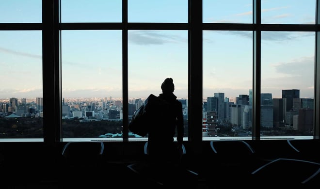 man standing with pack in front of city skyline