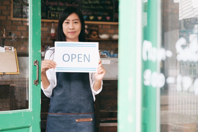 business owner holding Open sign in front of door 